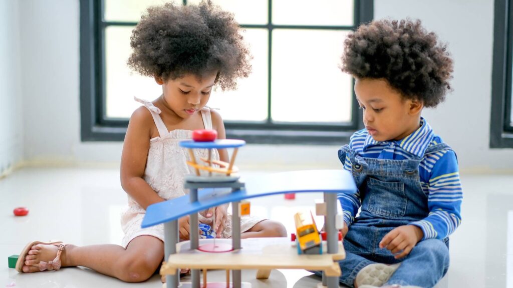 two kids playing together, curly hair, girl with a withe dress and boy with blue strippy shirt